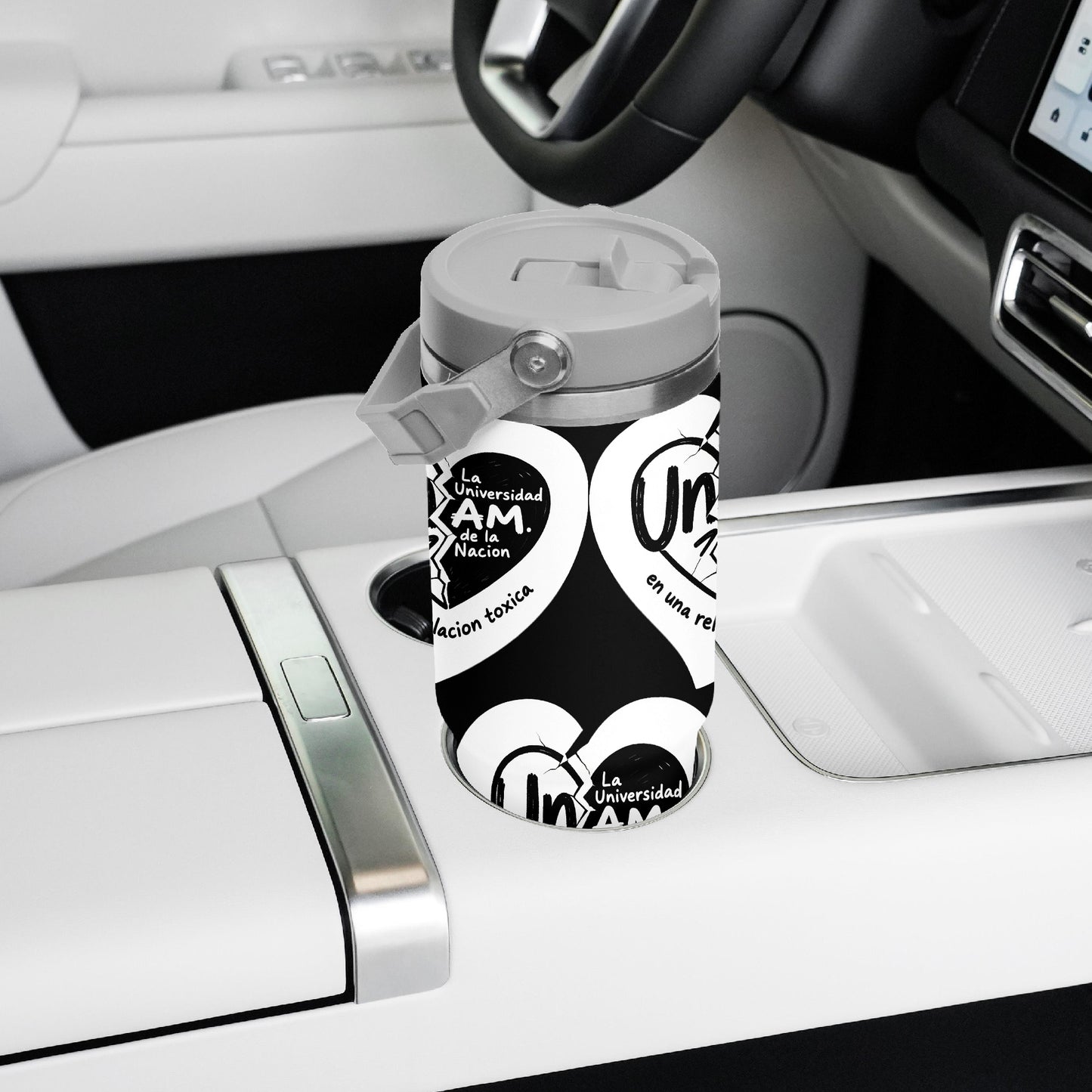 Black and white branded cup holder cover in a car.
UNAM