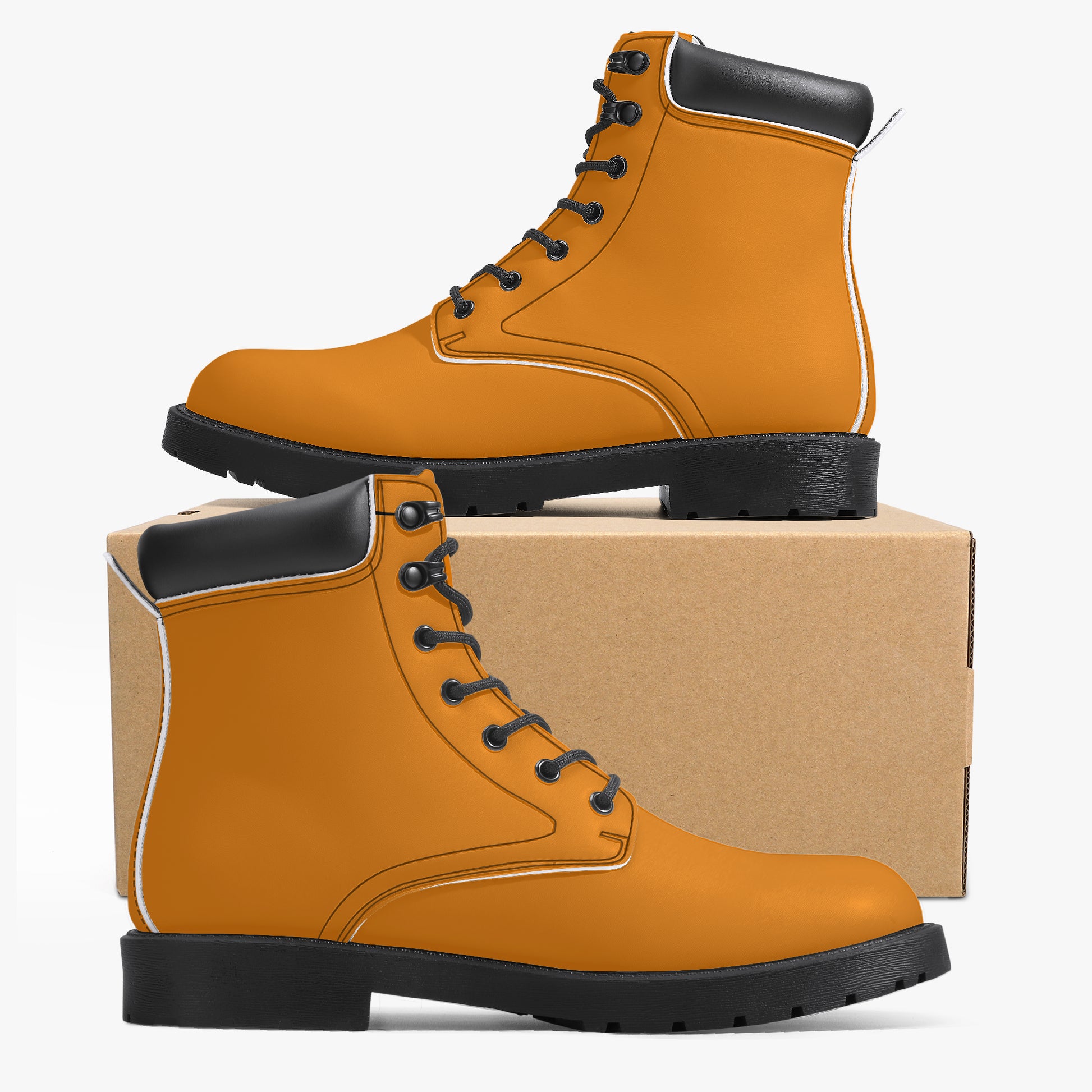Pair of orange work boots with black soles on a cardboard box against a white background