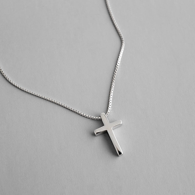 Silver cross necklace on a gray background
