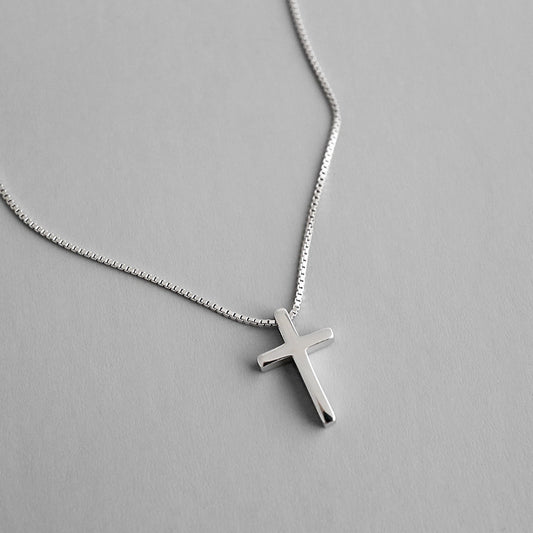 Silver cross necklace on a gray background