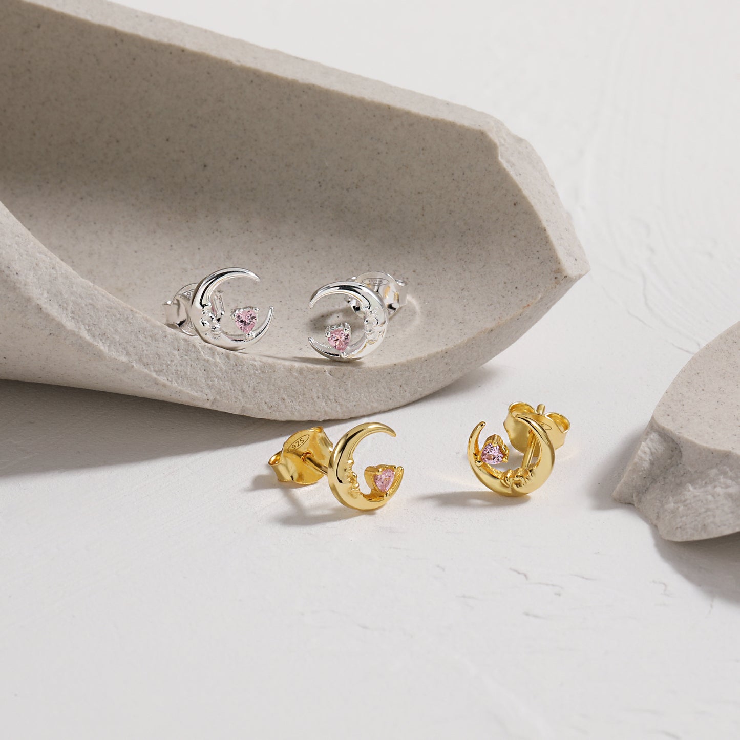 Gold and silver Crescent Moon earrings with pink gemstones on a light background