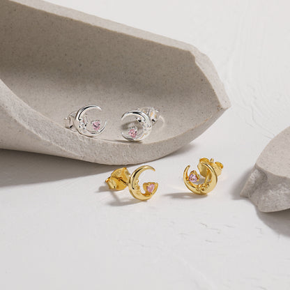 Gold and silver Crescent Moon earrings with pink gemstones on a light background