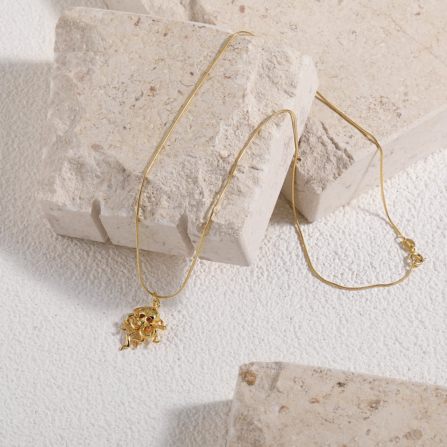 Gold octopus necklace on a chain against a white background- Front View- On Marble Slab