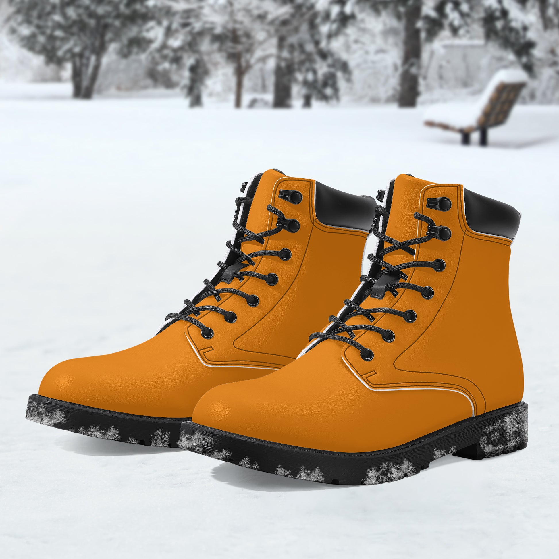 Pair of orange boots with black soles on a snowy background